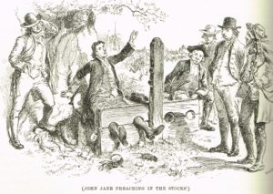 An engraved image of John Jane preaching from the stocks.